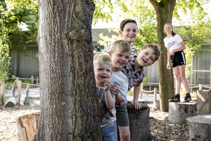 Leerlingen poseren op de speelplaats van De Brem achter een boom.